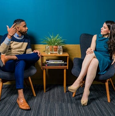 Image of an African American man and a white female having a discussion for the blog "Cultural Competency Training for Hiring Managers is Essential to Building a Diverse Workforce"