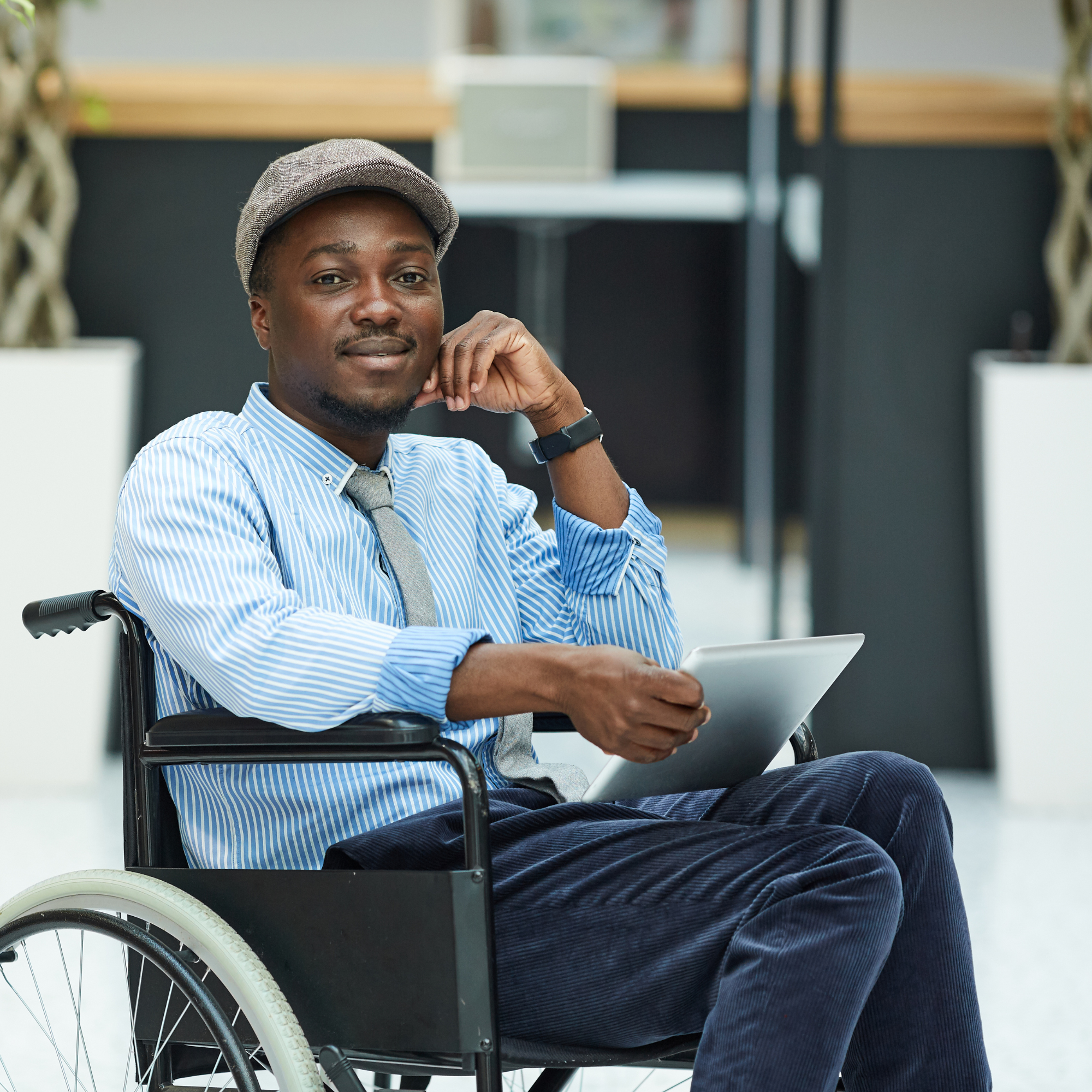 Image of an African American man in a wheelchair holding a tablet and smiling into the camera for the blog "Unconscious Bias Can Affect Hiring Decisions, but What Does It Look Like?"