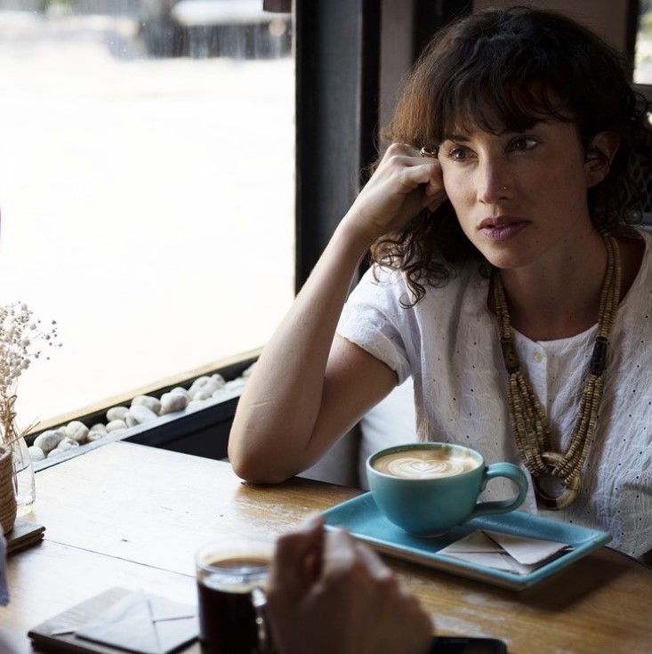 Image of a woman at a coffee shop in a discuss with another person off-camera for the blog "Conversation with a Seasoned Human Resource Colleague about DEI Progress – in the Tech Industry and Beyond"