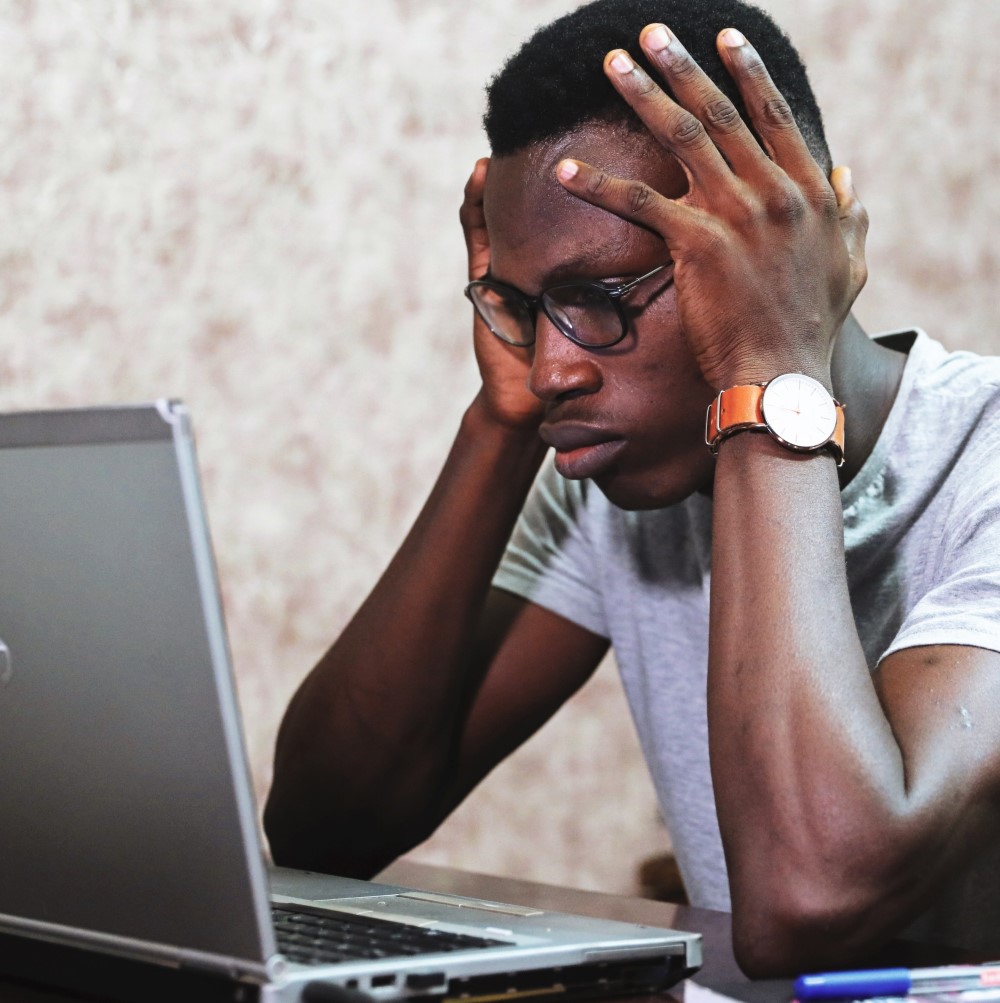 Image of a black male looking frustrated at a laptop computer for the blog "Would You Answer Certain Interview Questions Truthfully If You Were in the Applicant’s Shoes?"